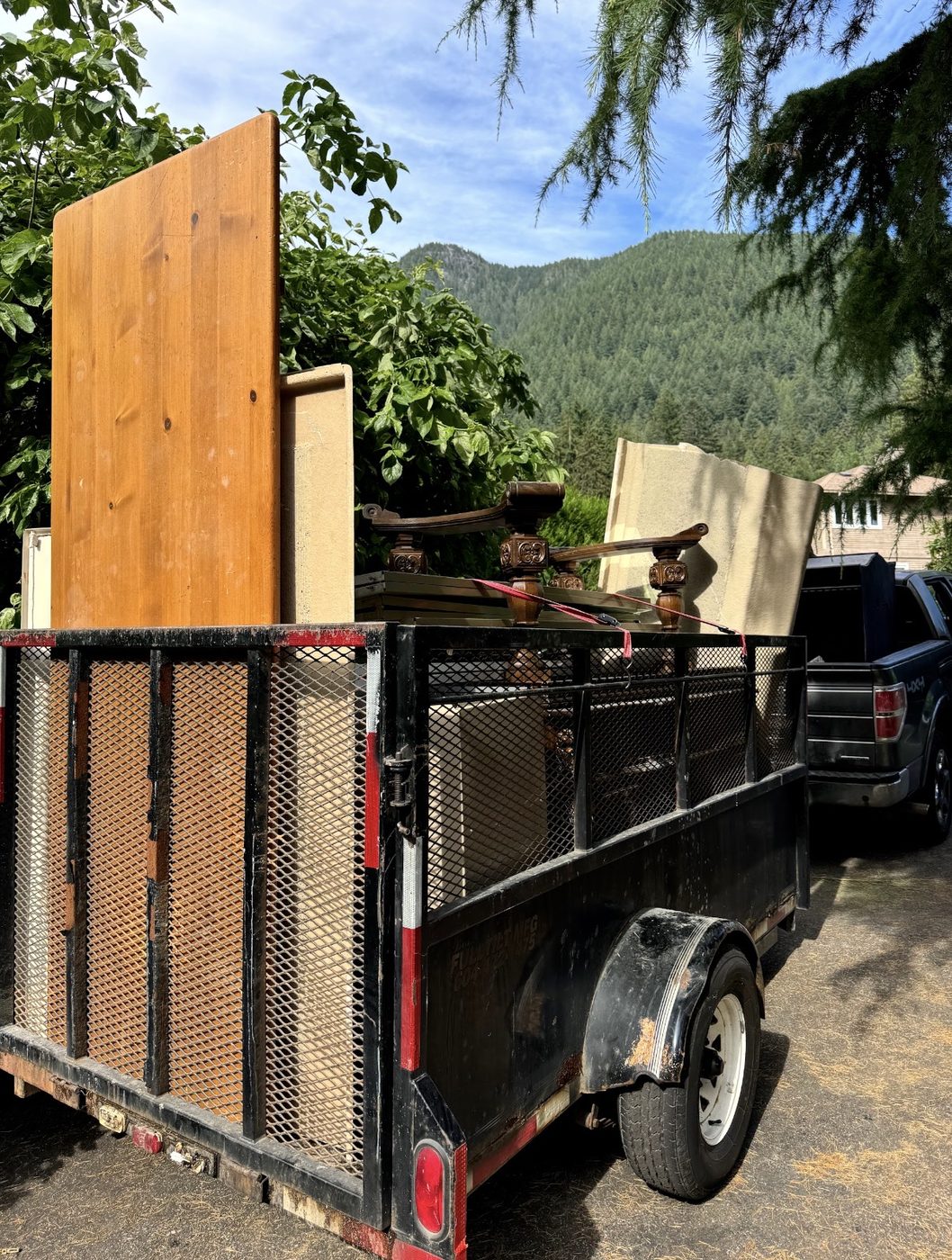 Trailer loaded with old wooden furniture and an antique chair after a home cleanout